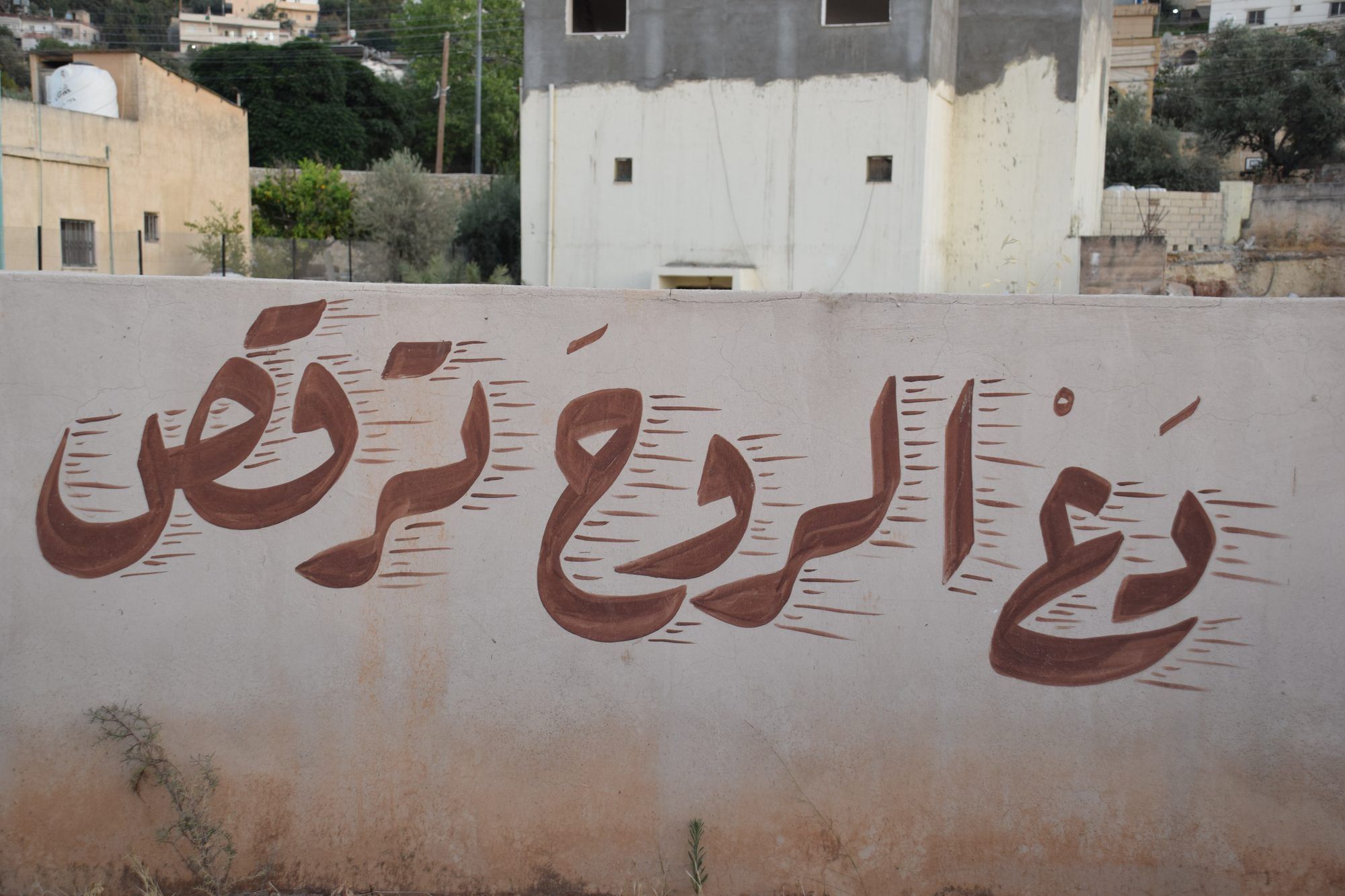 عبارة دع الروح ترقص مكتوبة بالخط العربي على جدار في الفحيص